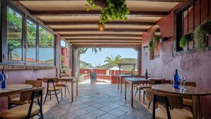 Un restaurante con terraza, suelo de piedra y vistas a las colinas.