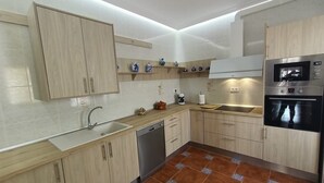 A modern kitchen with light wood cabinets, a stainless steel oven, and a dishwasher. - Holiday Home 'Batalla Navas de Tolosa' with Mountain View, Pool & Wi-Fi (Santa Elena)