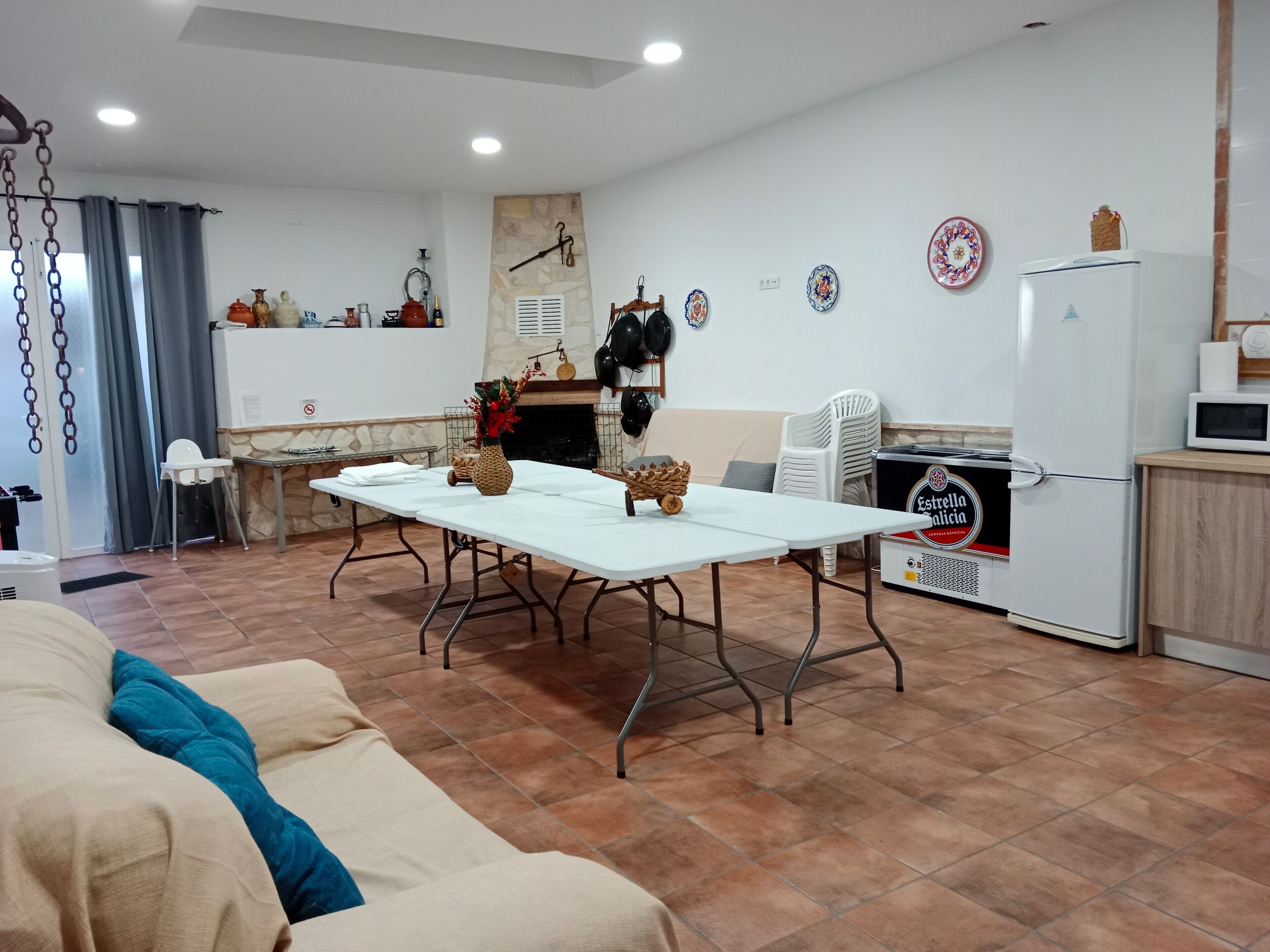 A dining area with a table set for four, a refrigerator, and a microwave.