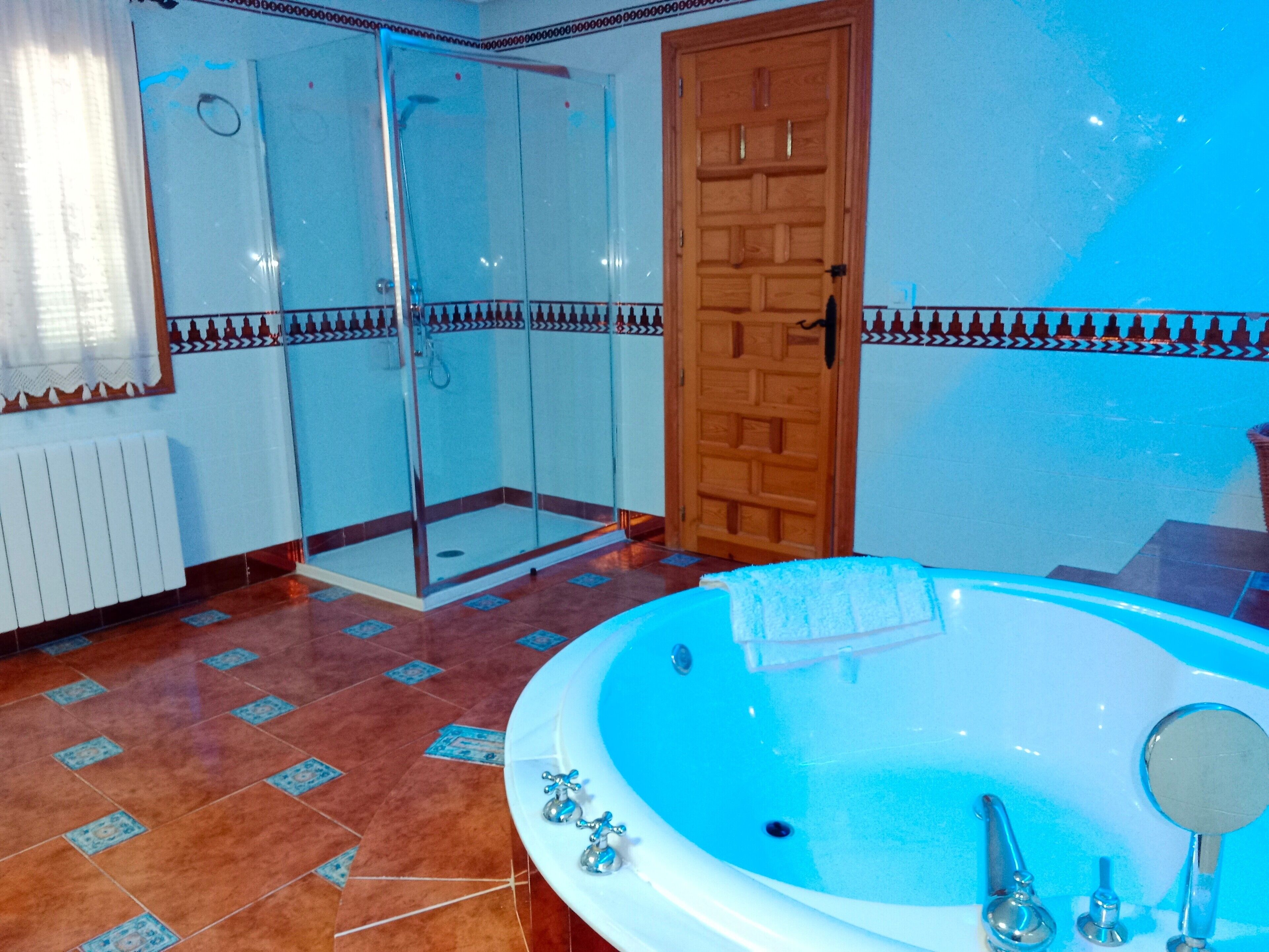 Un baño con ducha de vidrio, puerta de madera y bañera.
