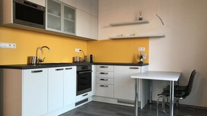 A modern kitchen with white cabinets, a black countertop, and a built-in oven.
