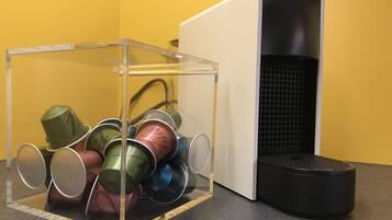 A clear plastic storage box with metal cups inside, placed on a black countertop next to a black and white speaker.