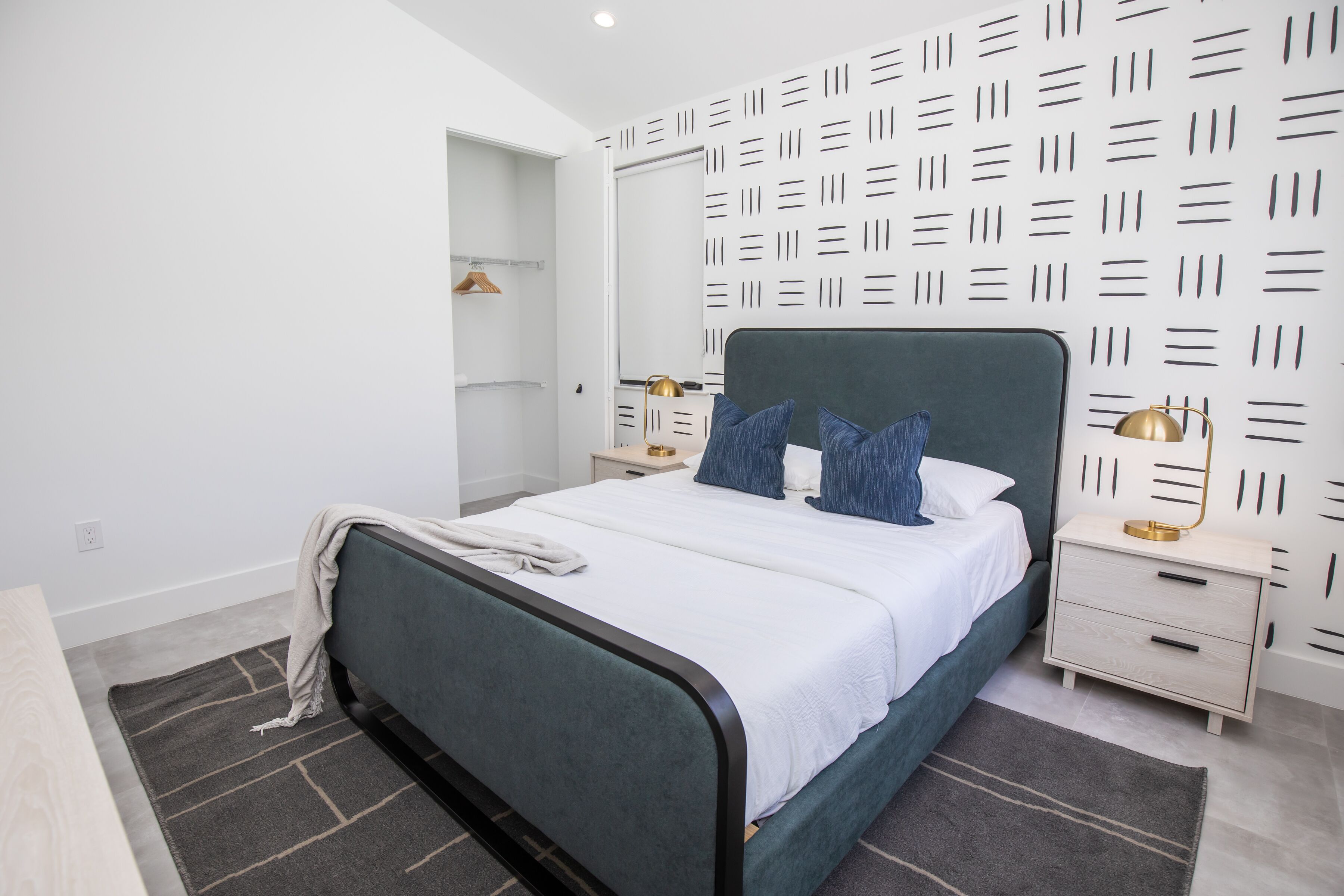 A modern bedroom with a bed, nightstands, and a wardrobe.