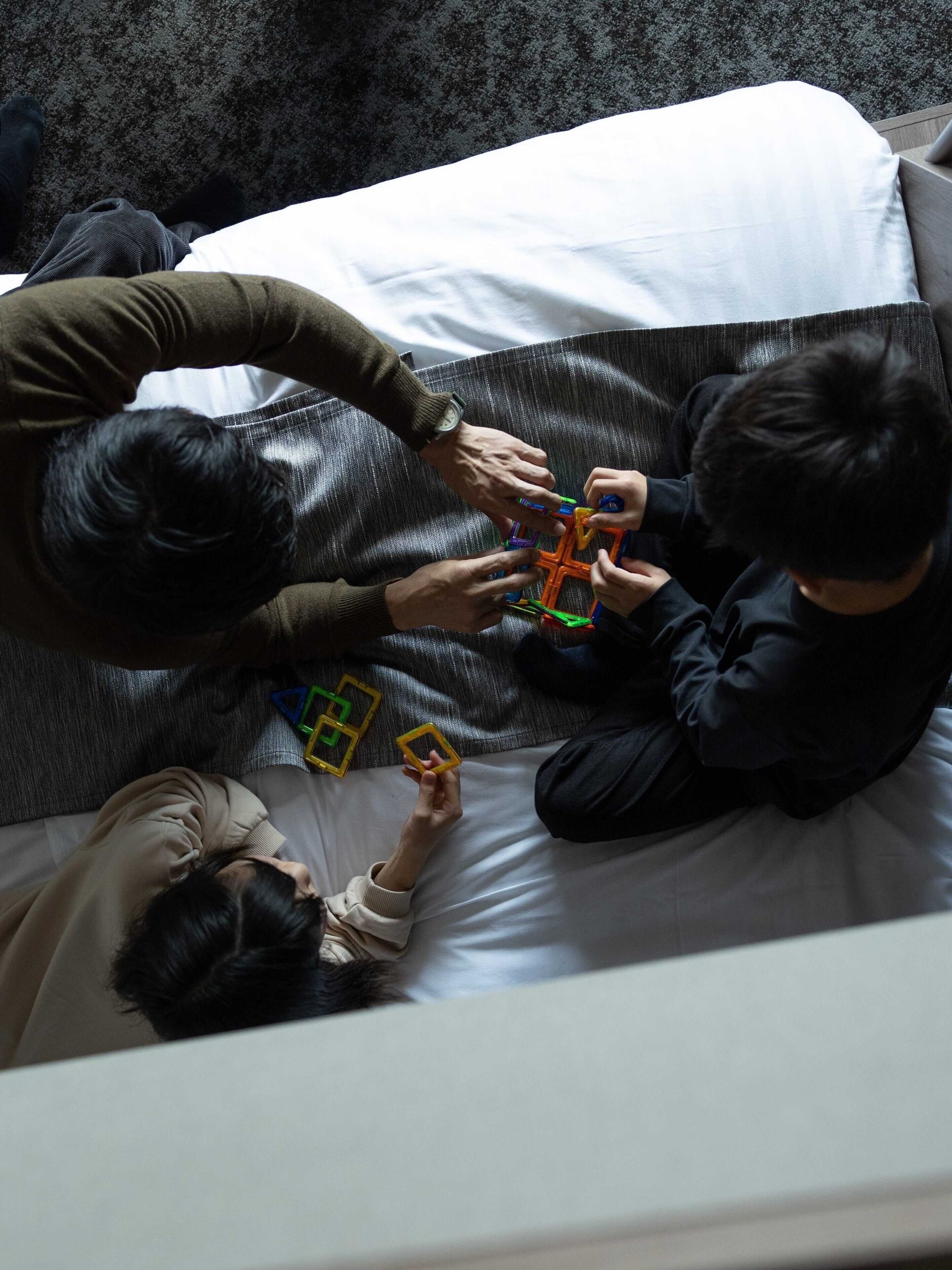 A person lying on a bed with a pillow, holding a toy.