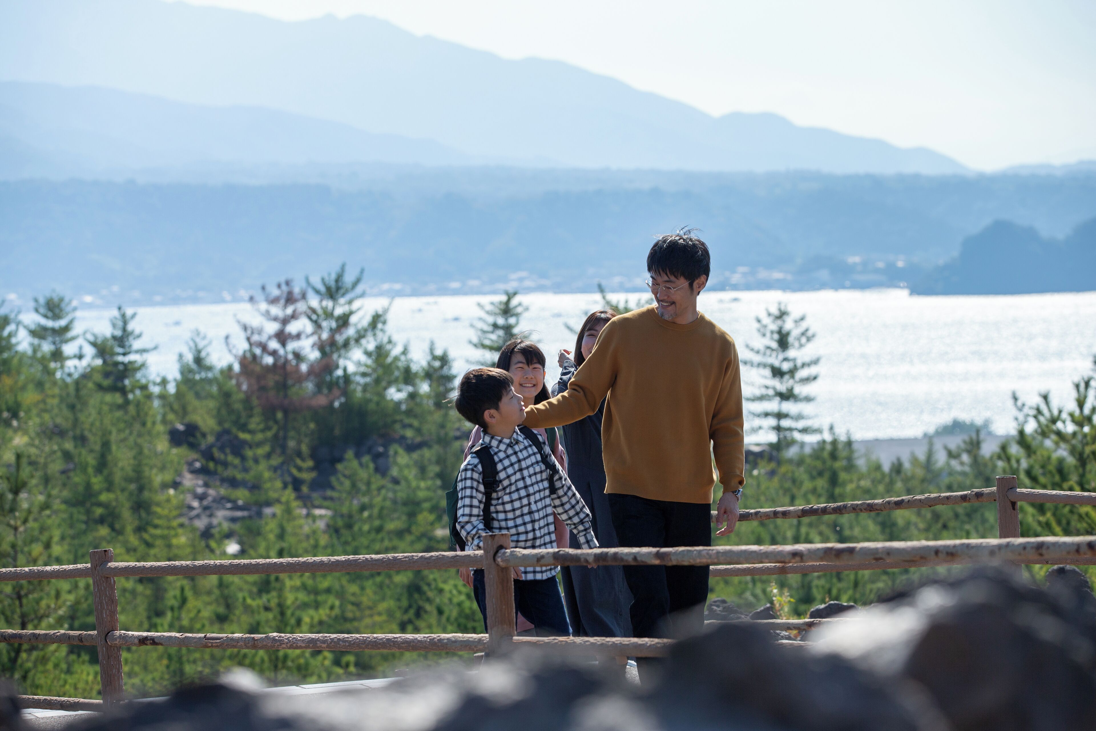 A wooden railing overlooking a lake with mountains in the background.