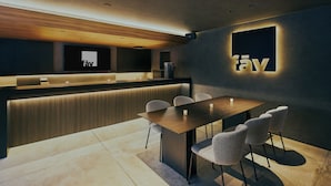 Ein moderner Empfangsbereich mit einem Holzbüro, einer Sitzecke mit Stühlen und einem großen Bildschirm, der das Logo 'fay' zeigt.