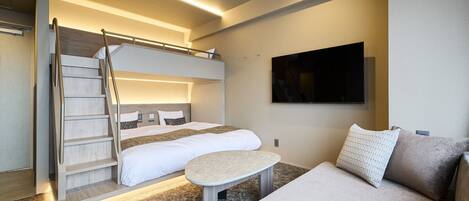 A modern hotel room with a bunk bed, a small table, and a flat-screen TV mounted on the wall.