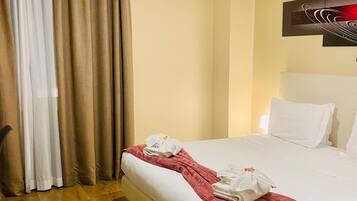 Quarto de hotel com uma cama grande, um cobertor vermelho, almofadas brancas e uma pintura na parede.