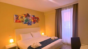 Een hotelkamer met een bed, nachtkastjes, een bureau en een raam met gordijnen.