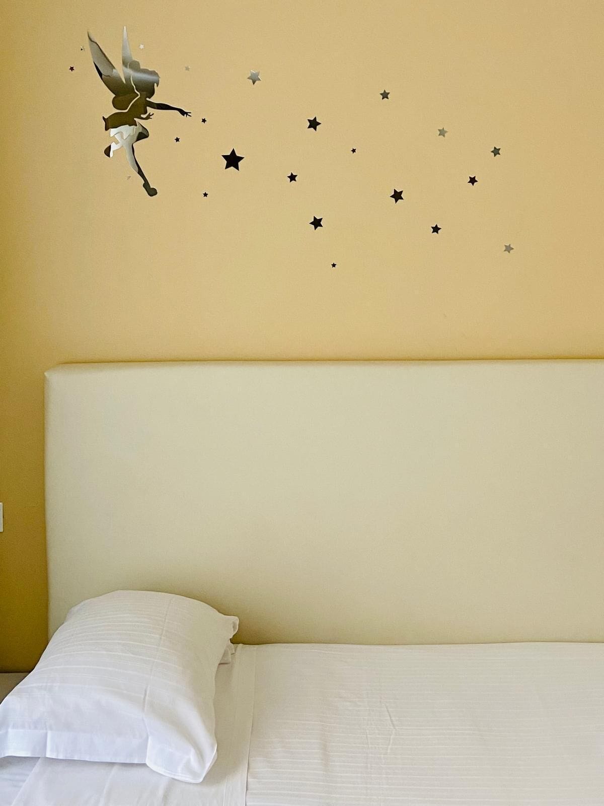 A bedroom with a bed, a headboard, and star-shaped wall decals.