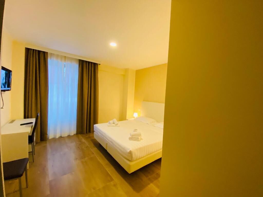 Una habitación de hotel con una cama, un escritorio y una silla.