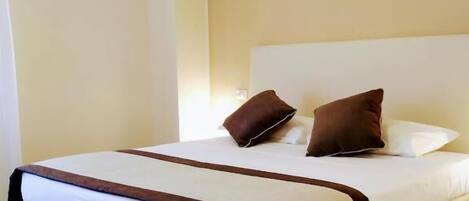 Habitación de hotel con una cama grande, suelo de madera y pared lisa.