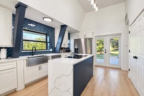 A modern kitchen with a central island, stainless steel appliances, and a view to the outdoors. - Modern Home - 1 Acre Lot w/ Pool, Patios, Jacuzzi (Denton)