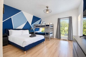 A modern bedroom with a bunk bed, a large bed, and a view of greenery through the window. - Modern Home - 1 Acre Lot w/ Pool, Patios, Jacuzzi (Denton)
