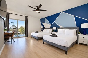 A modern hotel room with two beds, a dining area, and a balcony with a view.