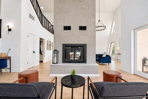 A spacious living room with a fireplace, a staircase, and a view of the outdoors. - Modern Home - 1 Acre Lot w/ Pool, Patios, Jacuzzi (Denton)