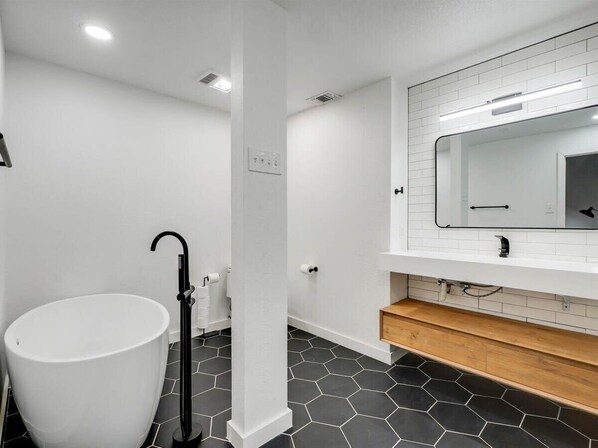 Une salle de bain moderne avec un lavabo blanc, des carreaux hexagonaux noirs et un meuble-lavabo en bois.