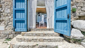 A stone building with a wooden staircase leading to a room with a window and a door.