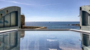 A pool with a clear view of the sea and a rocky coastline.