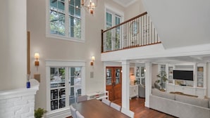 A spacious living area with a dining table, sofa, and TV. - Private Pool,LSV/Golf Cart, & 6 Bikes! Steps to Seaside in the Heart of Old Seagrove! (Santa Rosa Beach)