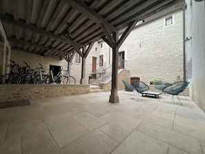 Un espace extérieur abrité, doté de murs en pierre, d’un escalier et de vélos.