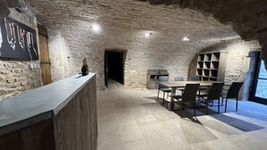 A rustic stone interior with a bar area, dining table, and chairs. - La Bastide De Chassagne-montrachet (Chassagne-Montrachet)