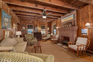 A cozy living room with wooden walls, a fireplace, and comfortable seating.