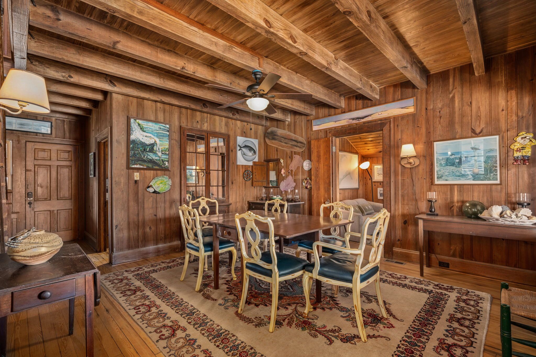 Une salle à manger en bois avec une grande table, des chaises et un ventilateur de plafond.