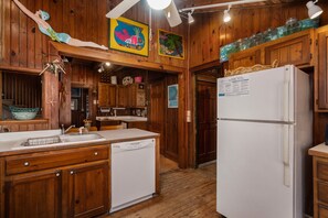 A kitchen with wooden cabinets, a white refrigerator, and a sink.