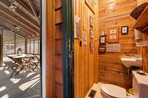 Un intérieur en bois comprenant un coin repas, une salle de bain avec un lavabo et des toilettes, et un mur en bois orné de tableaux encadrés.