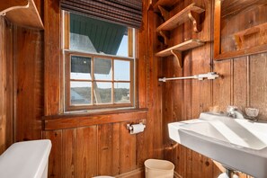 Une salle de bain en bois avec une fenêtre, un lavabo et des toilettes.