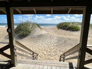 A wooden beach entrance with a view of the beach and ocean.