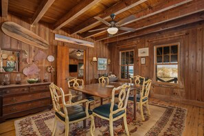 Un intérieur en bois avec une table à manger, des chaises et un ventilateur de plafond.