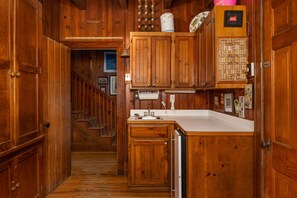 A wooden kitchen with a built-in dishwasher, wooden cabinets, and a white countertop.