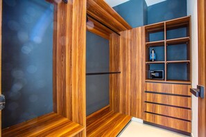 A room with a wooden wardrobe, a built-in safe, and a shelf unit.