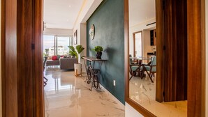 Een moderne hotellobby met een marmeren vloer, een groene accentmuur en een eetgedeelte met houten meubels.