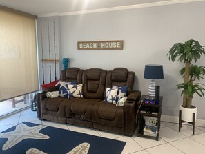 Relax in this beach-inspired living room with a comfortable sofa, starfish-patterned pillows, and a cozy reading nook.