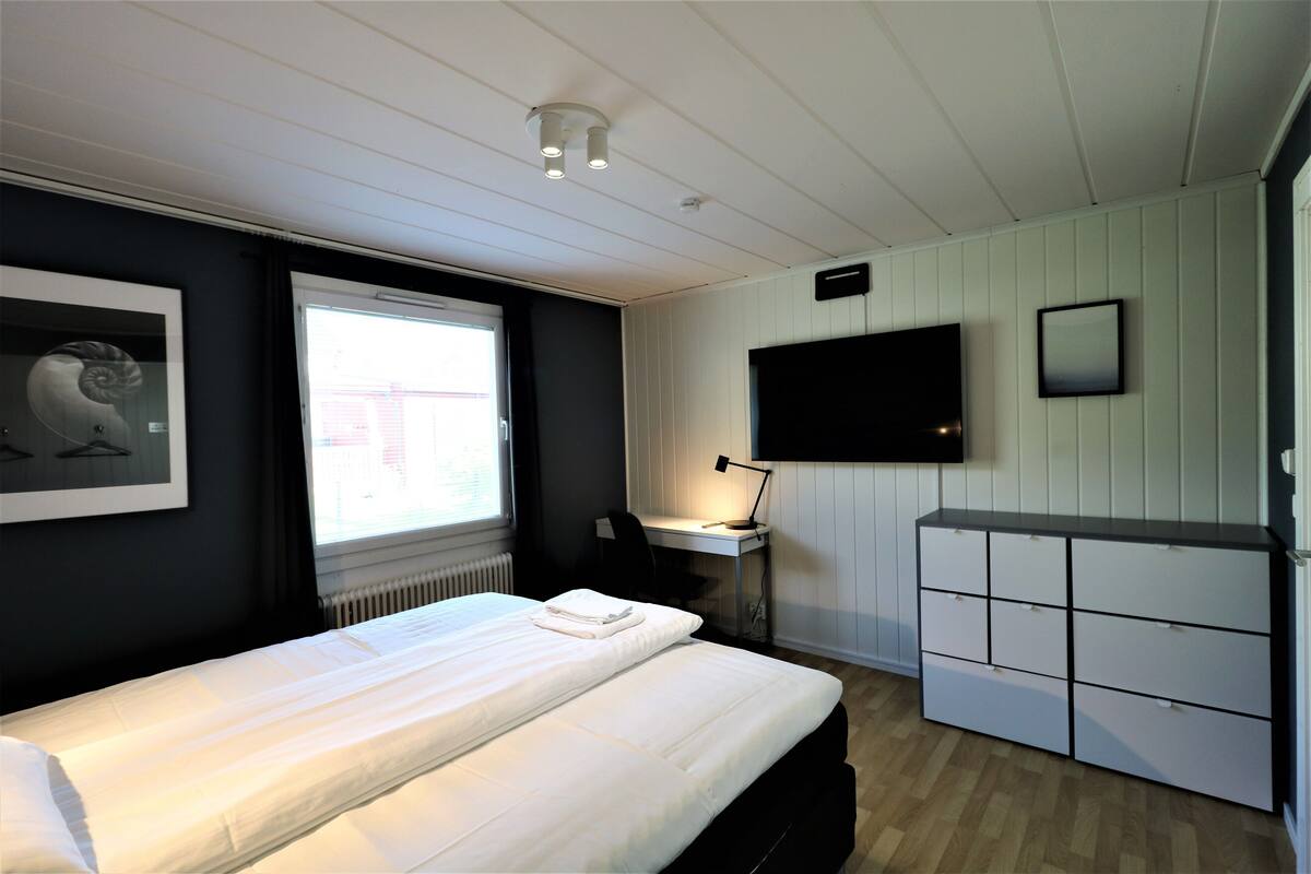 A bedroom with a bed, a desk with a computer, a TV, and a wardrobe.