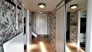 A hallway with floral wallpaper, a radiator, and a door labeled '5'. - RIBO Apartment Arctic - Hostel (Kiruna)