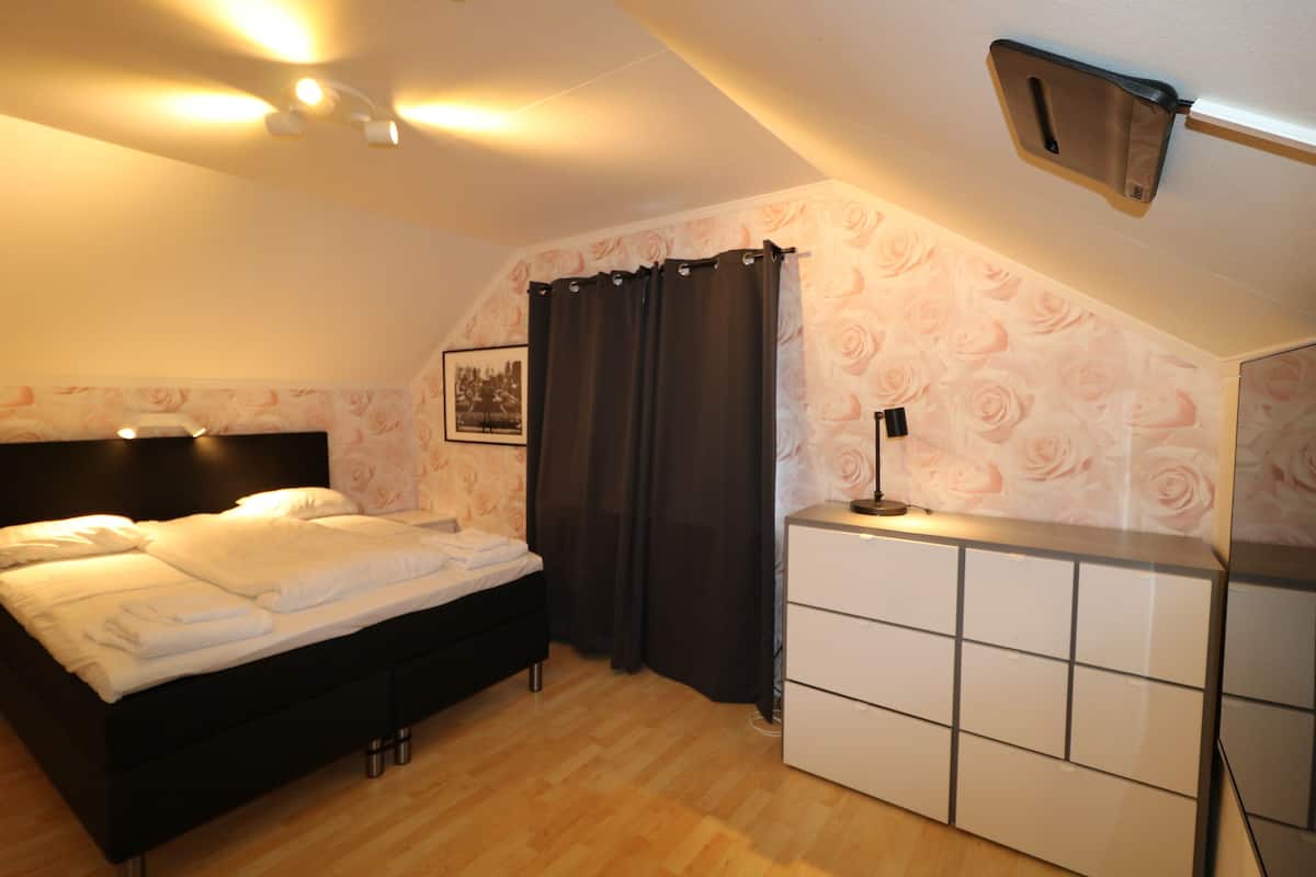 A bedroom with a bed, a dresser, and a ceiling light fixture.