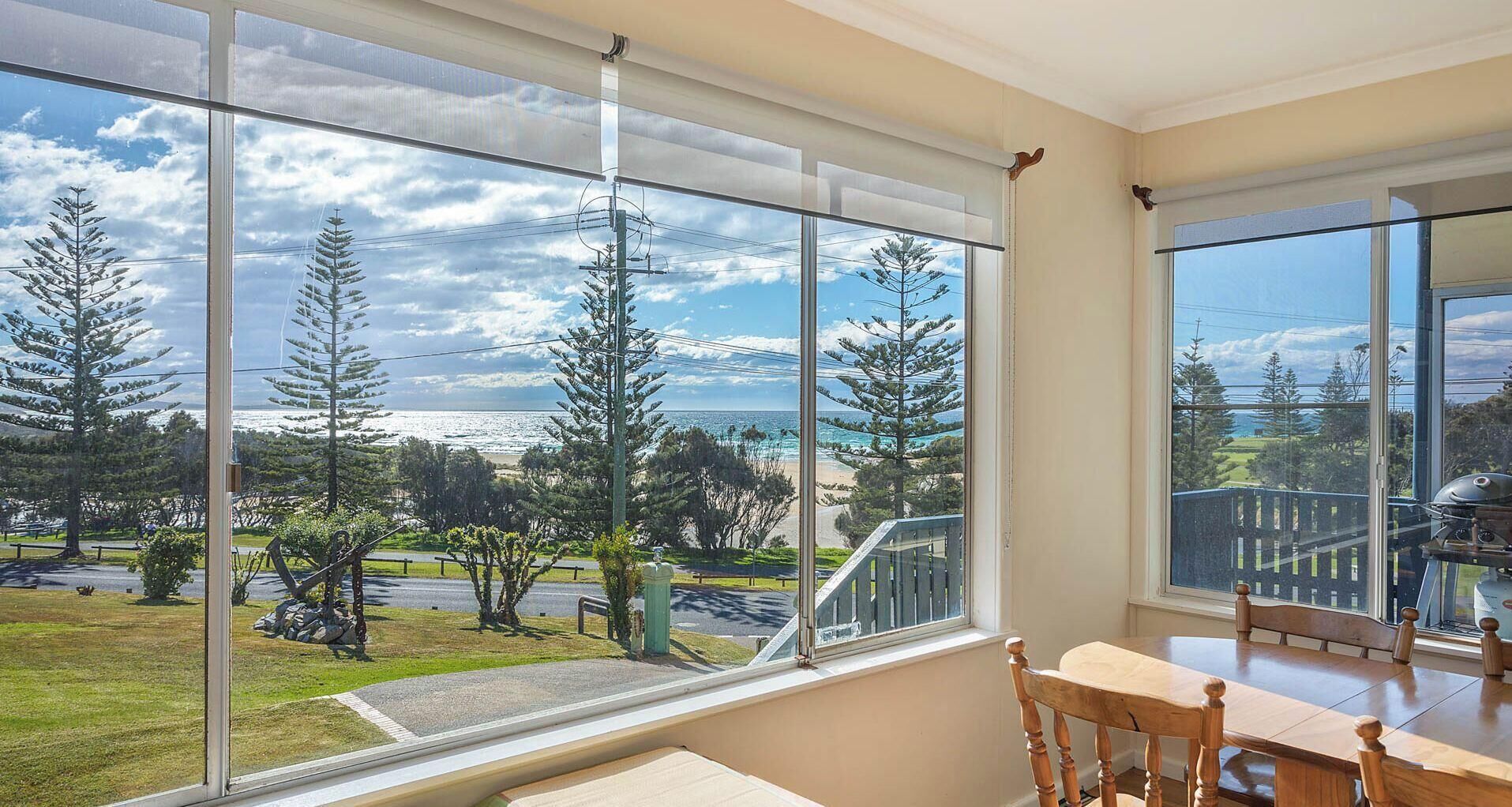 A room with large windows offering a view of a beach and trees.