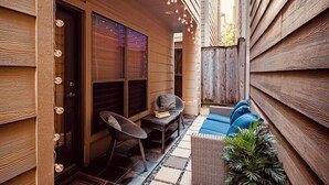 Een houten gevel met een overdekte patio, compleet met een zithoek, een klein tafeltje en sfeerverlichting.