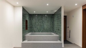 A modern bathroom with a glass-enclosed shower, a built-in bathtub, and a small wooden shelf. - Moor Hotel by Anook Mokpo (Mokpo)