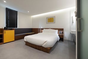 A modern hotel room with a large bed, a seating area with a bench, a small desk, and a window with blinds. - Moor Hotel by Anook Mokpo (Mokpo)