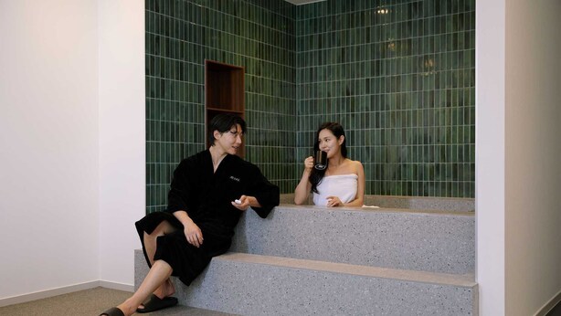 Two people sitting on a staircase in a room with green tiled walls. - Moor Hotel by Anook Mokpo (Mokpo)