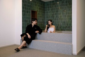 Two people sitting on a staircase in a room with green tiled walls. - Moor Hotel by Anook Mokpo (Mokpo)