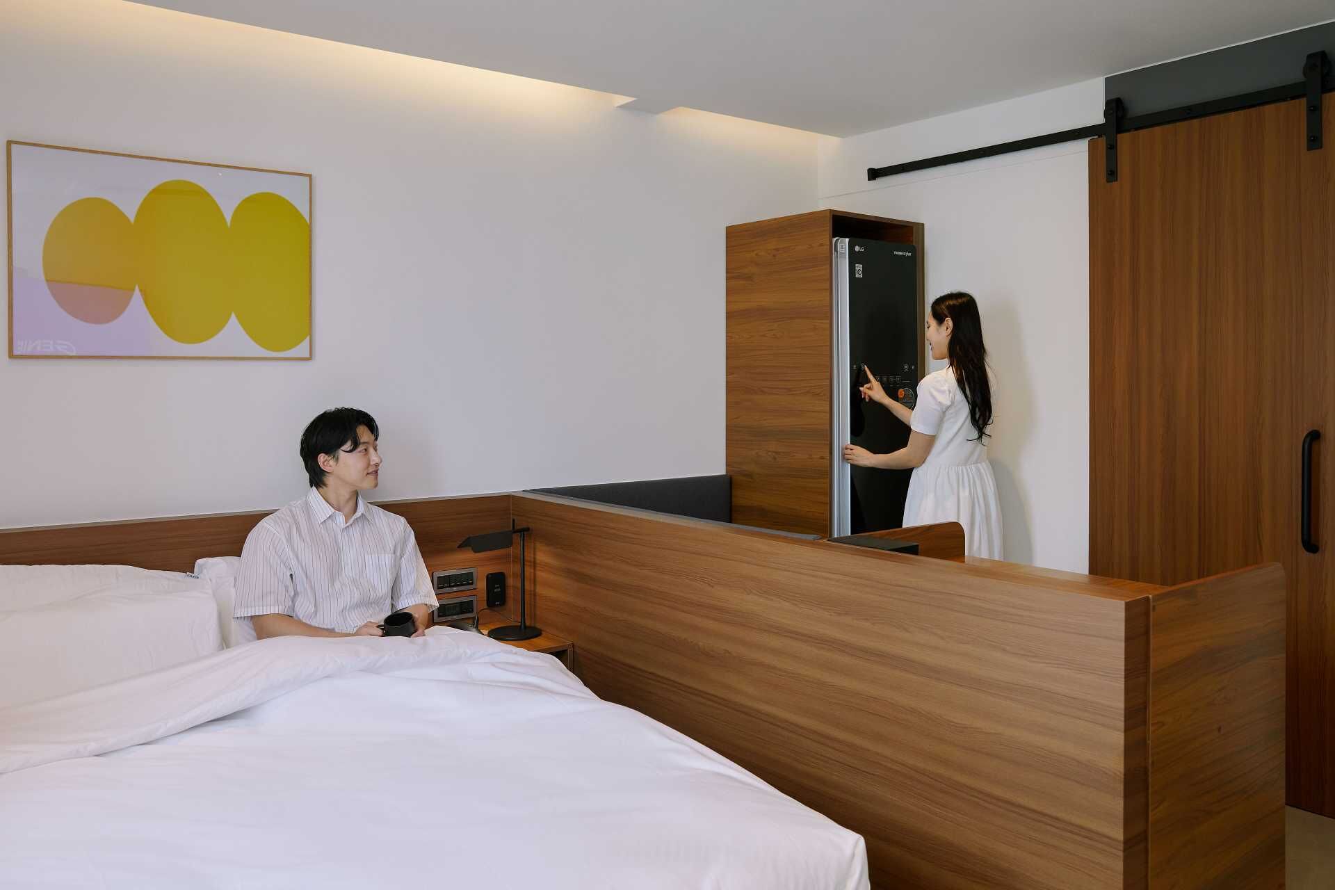 Quarto de hotel com cama, escrivaninha, guarda-roupa de madeira e porta deslizante.