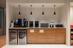 Ett litet kök med kaffebryggare, mikrovågsugn och kylskåp. Ovanför bänkskivan hänger fyra hänglampor.