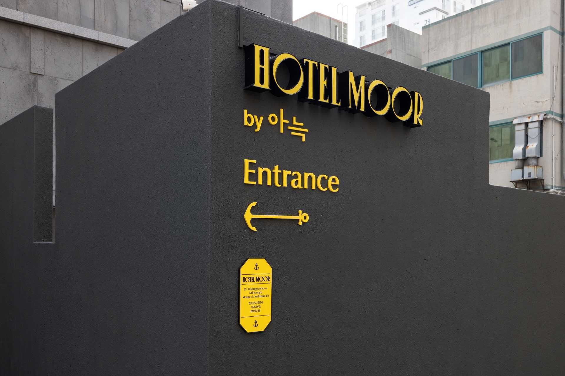 A hotel entrance sign with the name "HOTEL MOOR" and an arrow pointing to the entrance.