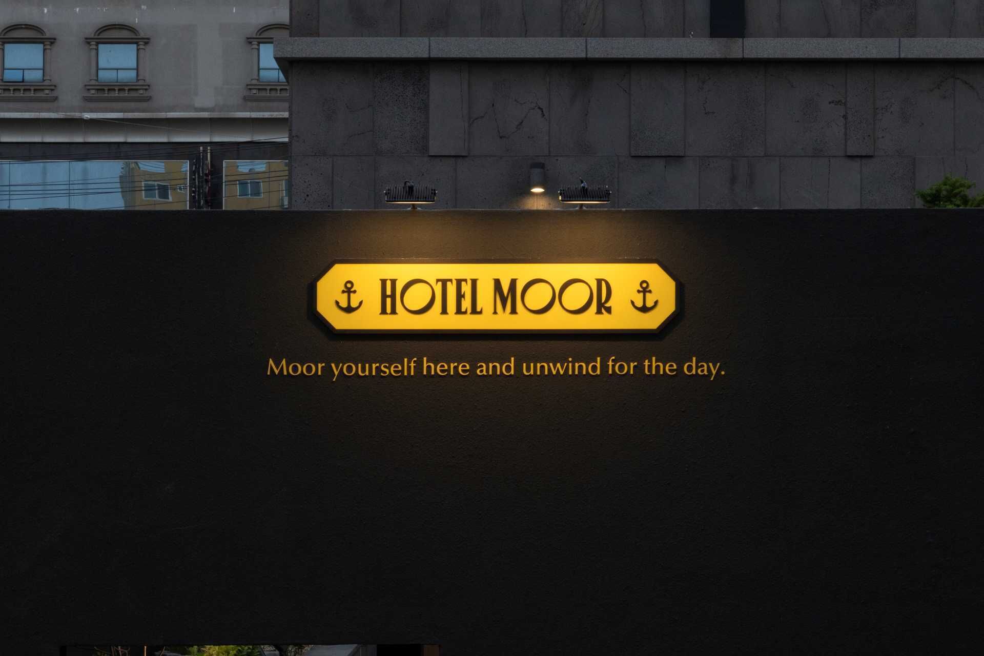 Un letrero de hotel con el nombre "HOTEL MOOR" y la frase "Ancla aquí y relájate por el día".